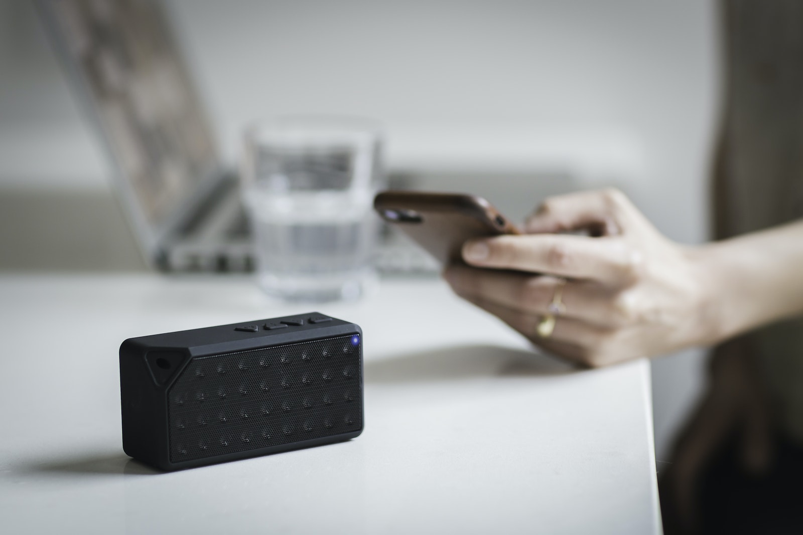 Person Holding Iphone Beside Black Portable Speaker
