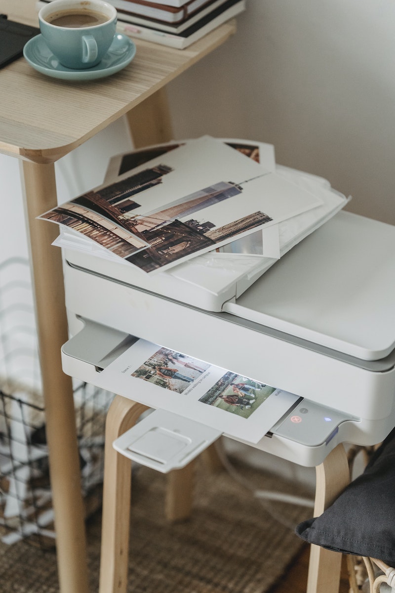 Photos placed on printer near table with cup of coffee